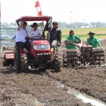 Bersama para petani Ugi Sugiharto didampingi oleh Ir Tisna Umaran,MP menaiki traktor besar untuk mengolah tanah dengan volume air sedikit saja (Foto:sembada/rori)