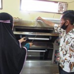 Ketua KWT Hasrat Rahma Bakery (kiri) dibantu Ketua Kelompok Tani Hasrat  Jufri Harun sedang mengangkat kue pia dari UPH oven (Foto:sembada/rori)