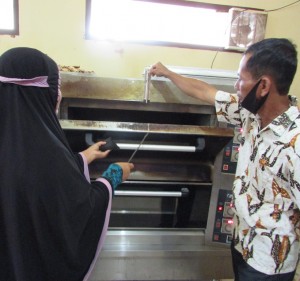 Ketua KWT Hasrat Rahma Bakery (kiri) dibantu Ketua Kelompok Tani Hasrat  Jufri Harun sedang mengangkat kue pia dari UPH oven (Foto:sembada/rori)