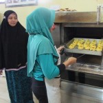 Maryam mendampingi pekerja yang sedang memasukkan kue yang baru dibentuk ke dalam oven (Foto:sembada/rori)